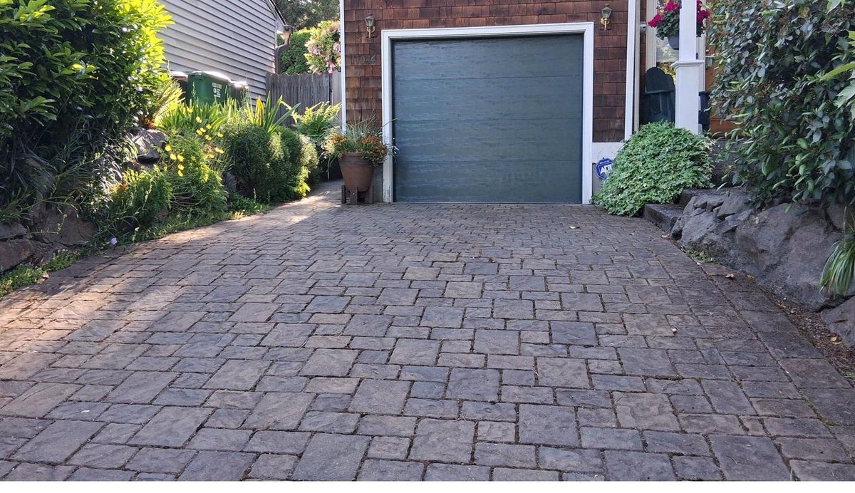Paver driveway leading to cedar shake home